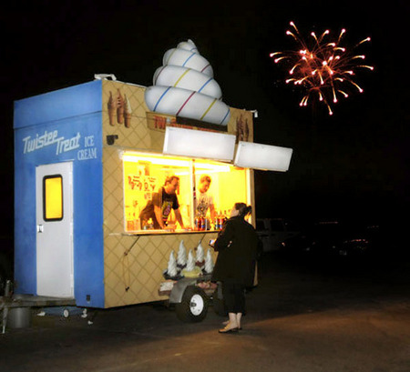 At the Sonoma- Marin County Fairgrounds Sunday, July 4, 2010, the interior light of an ice-cream concession glows brightly, while fireworks are ignited in the distance.  Nina Zhito  / for the Argus-Courier